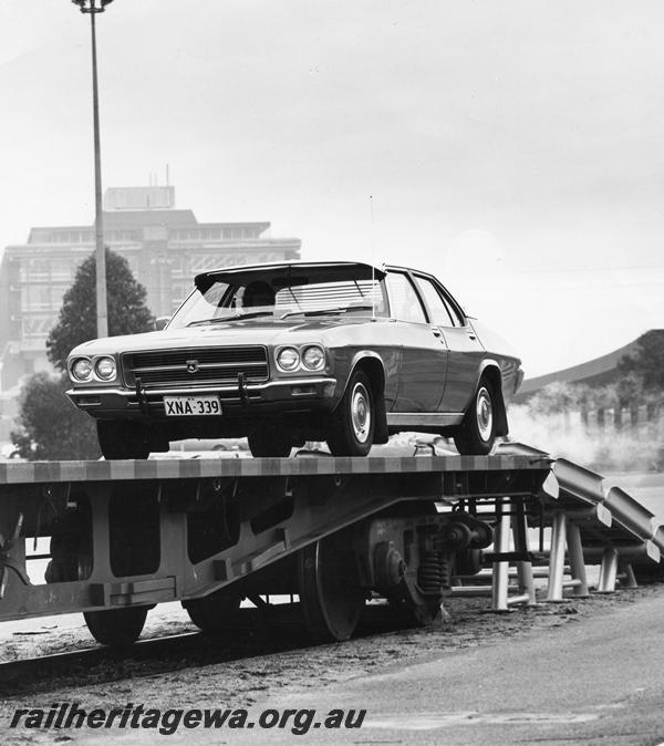 P00285
Holden car being driven up onto a standard gauge flat wagon, East Perth Terminal (Ref: 