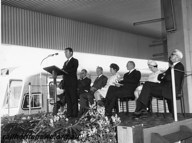 P00298
Ceremony for the launch of the Prospector railcar, East Perth Terminal, dignitary giving a speech, other official guests seated behind

