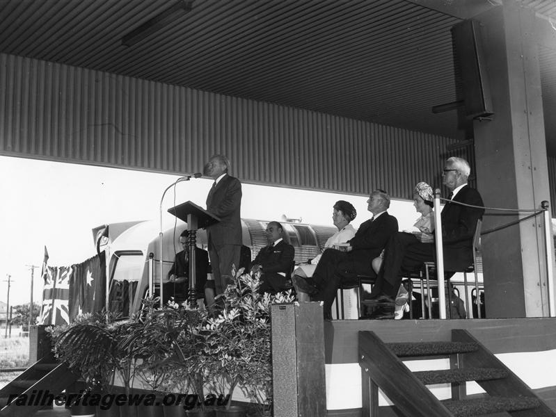 P00299
Ceremony for the launch of the Prospector railcar, East Perth Terminal, dignitary giving a speech, other official guests seated behind
