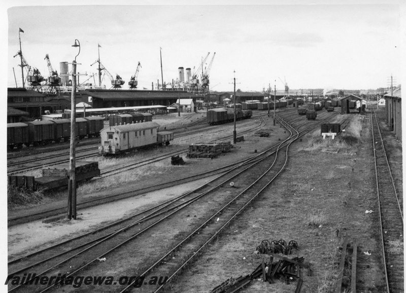P01725
Marshalling yard, Fremantle, ER line, E, F and G sheds in the background, VS class scale adjusters van and DX class weighbridge testing van in centre of the photo, view towards Perth. 
