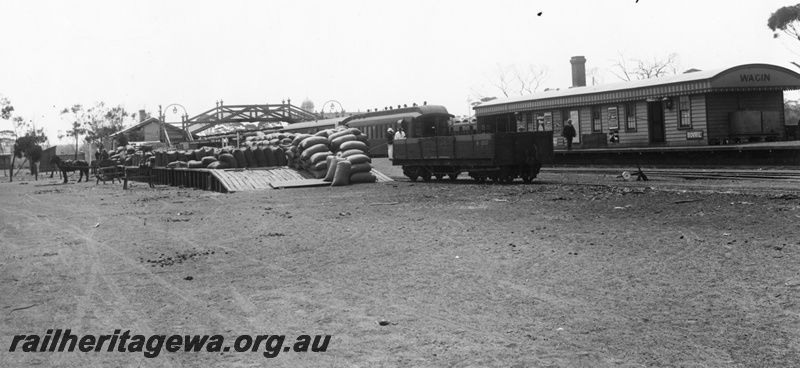 P02033
R class 2157 bogie open wagon, Gilbert carriage, station building, footbridge, loading platform with stacked bags, horse and cart, Wagin, GSR line, overall view of the station yard.
