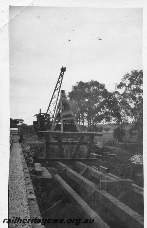 P02059
Trestle bridge, pile driving derrick being lifted into position by a steam crane, view along the deck from an adjacent bridge. Possibly Guildford
