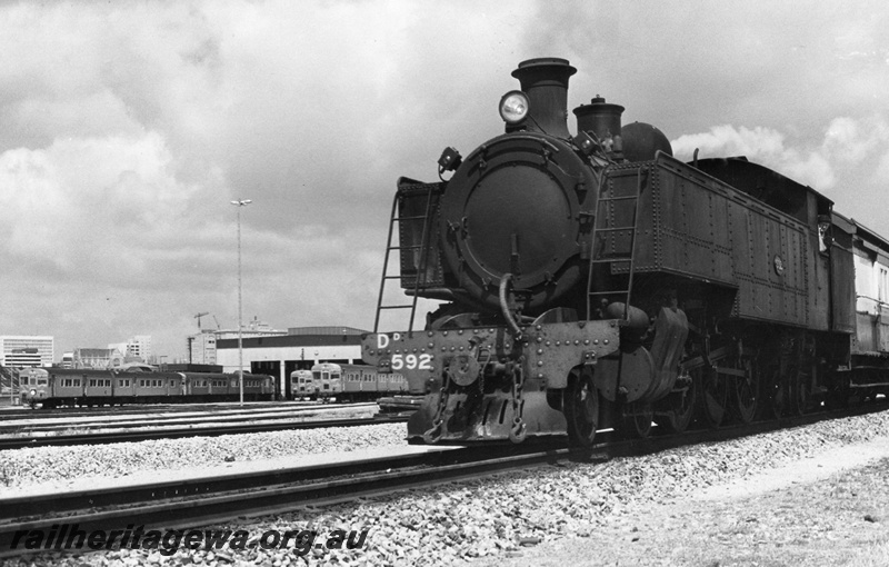 P02527
DD class 592 steam locomotive on suburban passenger working, front and side view, diesel railcars in the background, East Perth, ER line.
