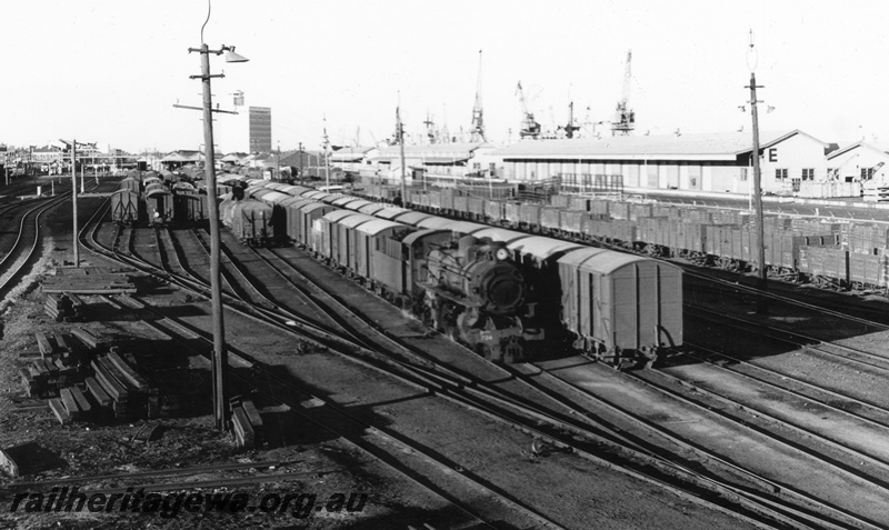 P02534
PMR class 724 steam locomotive, side and front view, Fremantle yard with lines full of rolling stock, E shed in the background, ER line. circa late 1960s.
