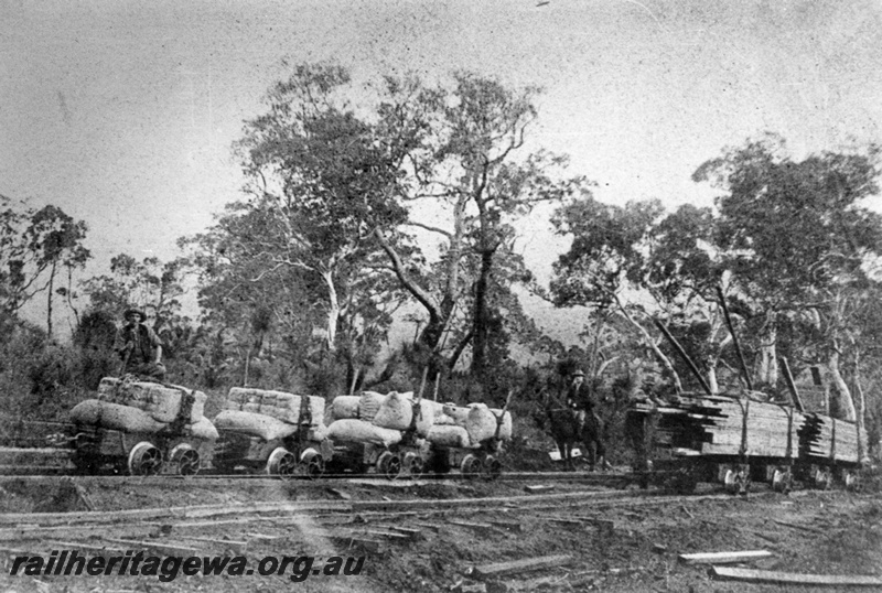 P03503
North Dandalup Incline, 4 wheel trucks with bagged loads with man riding on top of one truck, wagons with sawn timber on siding, Whittakers Mill.
