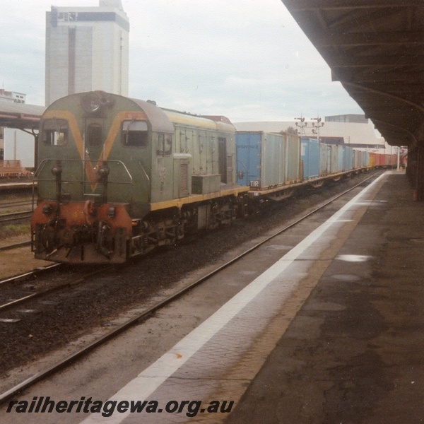 P04324
F class 43 diesel locomotive in green with red and yellow stripe livery, front and side view, on goods train passing through Perth station, ER line.
