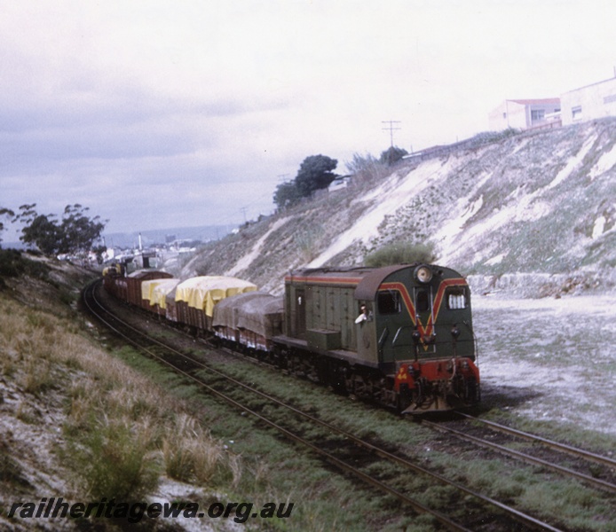 P04396
F class 44 diesel locomotive in green with red and yellow stripe livery, side and front view, on goods train in cutting near West Leederville, ER line.
