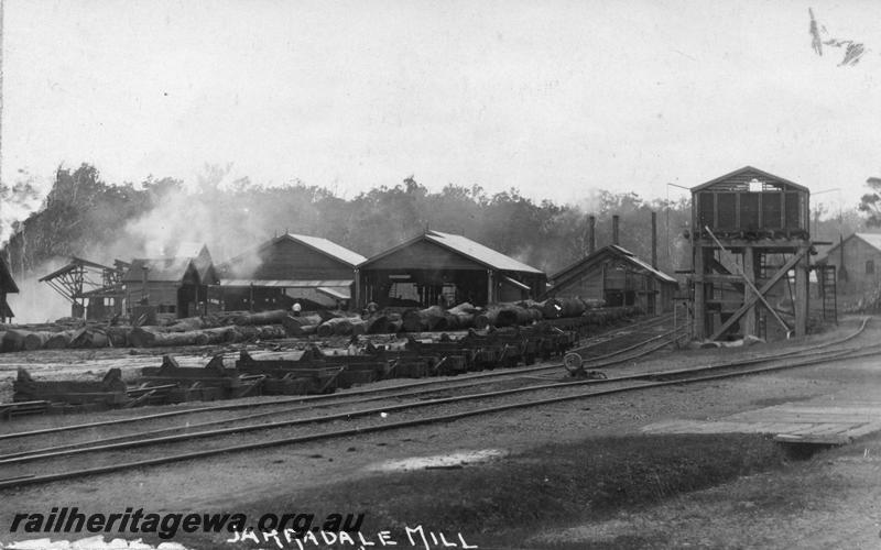 P07972
Mill, Jarrahdale, overall view, shows railway tracks in foreground, wooden water tank, log wagons, postcard.
