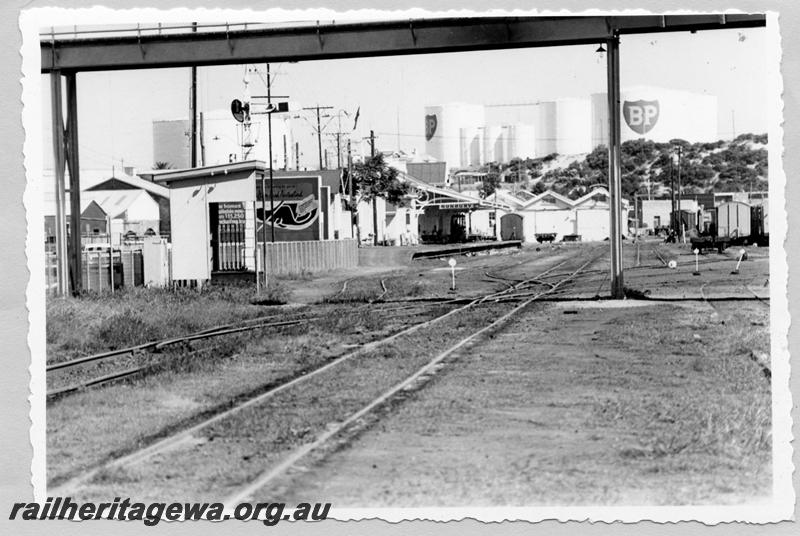 P09433
Bunbury, station buildings, platform, nameboard, lever frame, signal, goods sheds, wagons in yard, view from beyond footbridge, east end of yard. SWR line.
