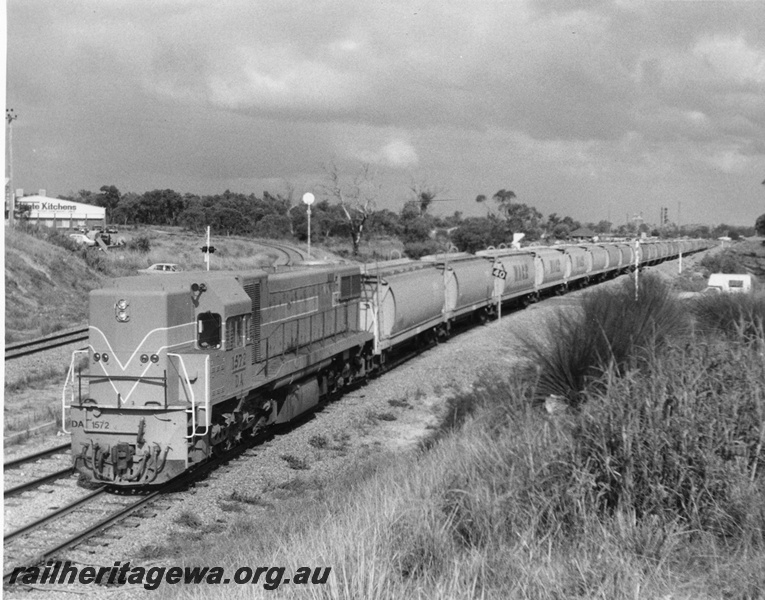 P10349
DA class 1572 Westrail Orange, short end and side view hauling class XW wheat wagons approaching Cockburn North Junction enroute to Forrestfield, North leg of Cockburn triangle visible in background. 
