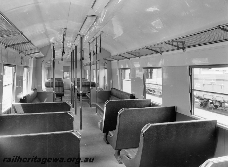 P10392
Interior view of a suburban railcar trailer showing crush barriers, standee straps and luggage racks.. Location Unknown.

