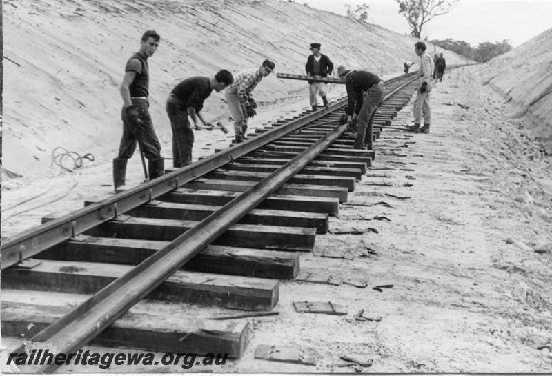 P12025
3 of 12 images of the construction of the Kwinana to Jarrahdale railway. (ref: The Railway Institute Magazine, July 1963), gangers laying the track, view shows the elastic dog spikes being fastened.
