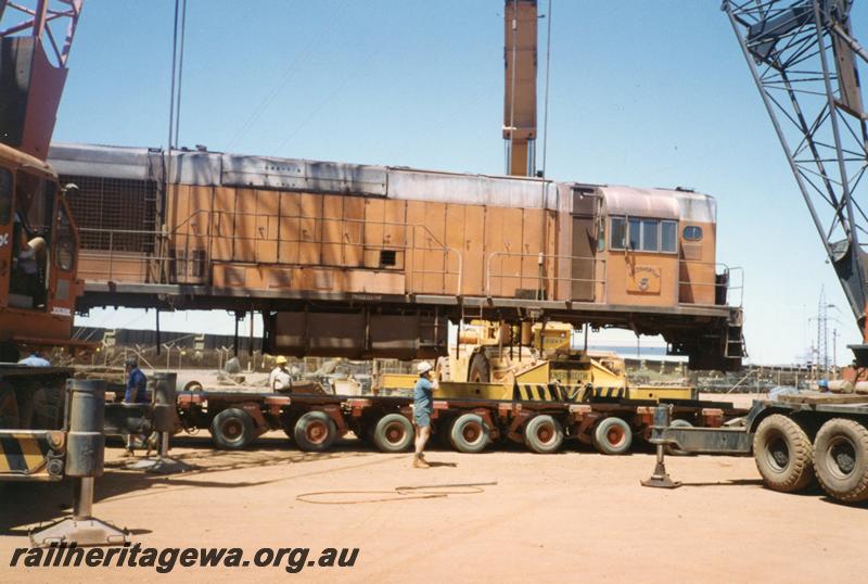 P12530
Port Hedland, Nelson Point, hard stand area, former Goldsworthy A class No.5 English Electric loco being loaded onto a road float for transporting south
