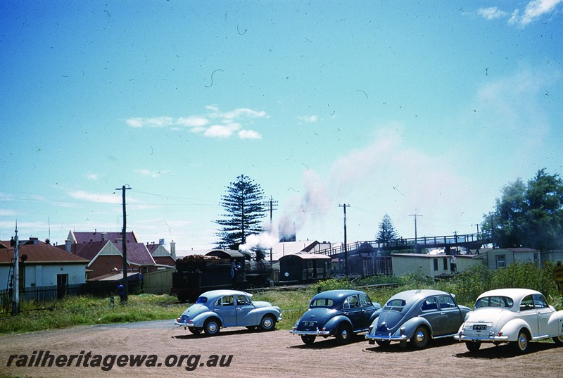 P13052
F class with wood fuel load in tender, Bunbury, SWR line, view of the rear of the tender. Three Morris Minor and a Volkswagen car in the carpark in the foreground.
