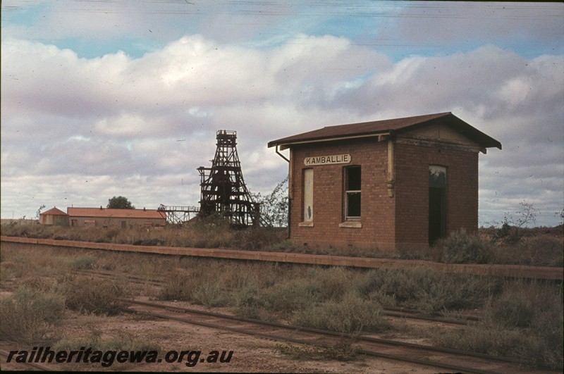 P13164
Station building with nameboard, platform, Kamballie, B line, view across the track, mine poppet head in background.
