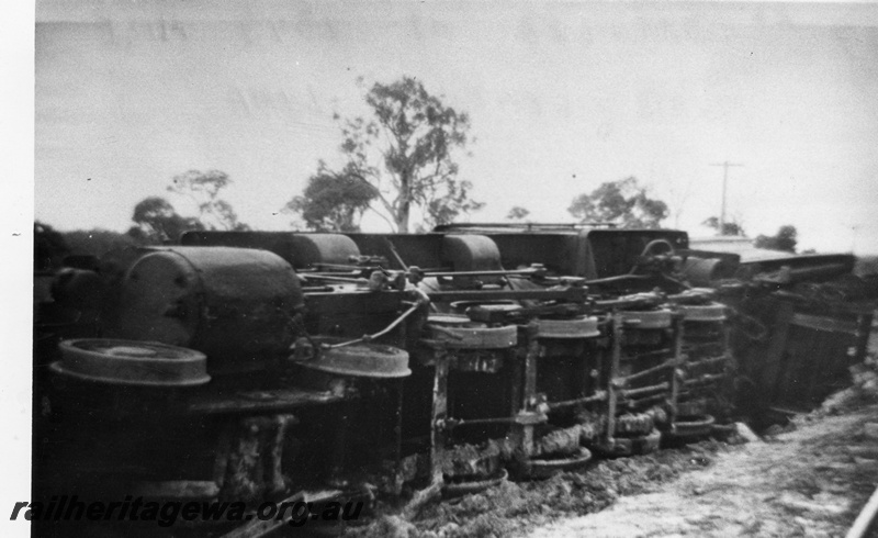 P14702
2 of 3, FS class 427 steam locomotive derailed near Muja on the Muja-Centaur-Collie line, BN line, view of the underneath of the loco and flangeless leaders.  Date of derailment 23/8/1955
