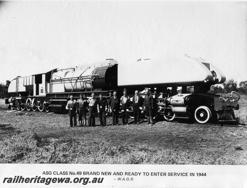 P14878
ASG class 49 Garratt articulated steam locomotive, brand new and ready to enter service, in photographic grey livery, men posing along side, side view, location Unknown.
