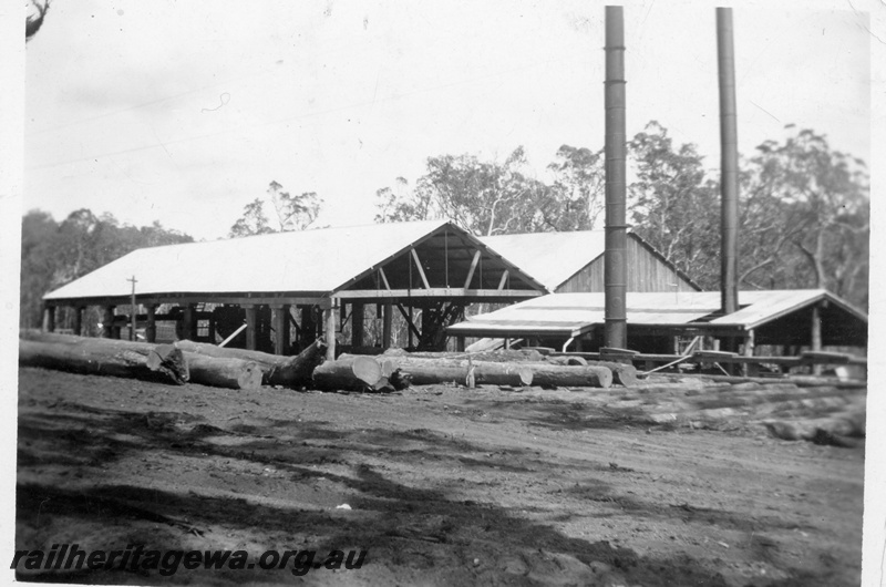 P14928
West end of the mill at Nyamup showing logs on the landing and the boiler room with the twin chimneys
