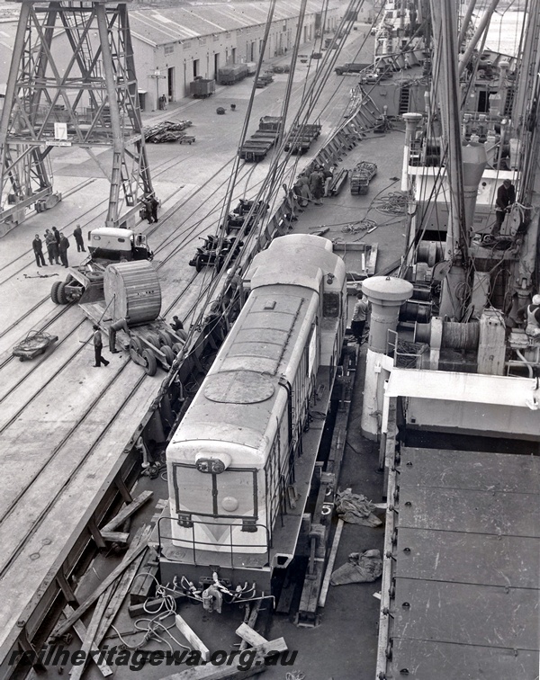 P15058
H class 4, on ship's deck, about to be unloaded, other cargo handling, crane (part), tracks and sheds on wharf, North Quay, Fremantle Port, c1967
