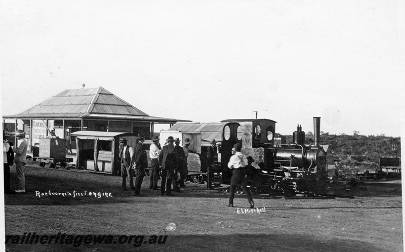 P15113
An unidentified steam locomotive, Roebourne's first, pictured outside a tailor shop. Note the flat wagon with a water tank as a load and the low level passenger vehicle adjacent.
