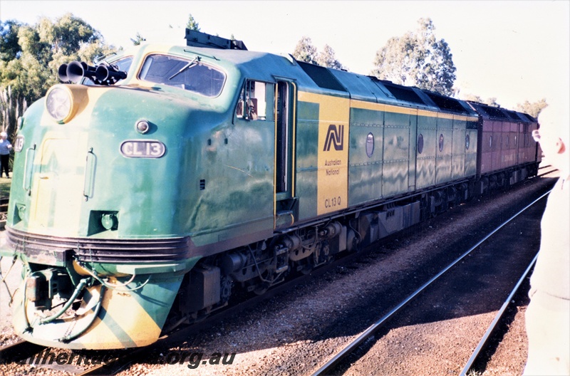 P15619
Australian National CL class 13 in the green livery with the yellow stripes on the nose an a yellow stripe and panel on the side coupled to a CL class in the marron and silver livery, East Perth Terminal, front and side view.
