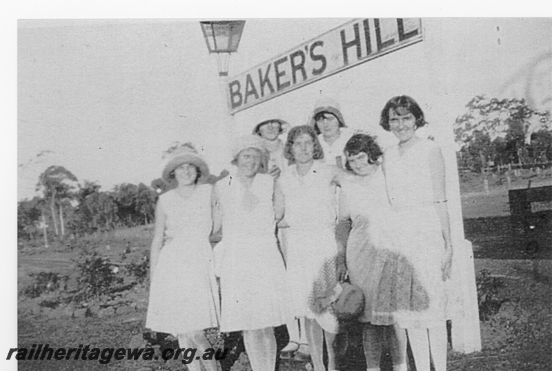 P15810
Station lamp, nameboard, Baker's Hill, ER line, a group of women posing beneath the nameboard, 