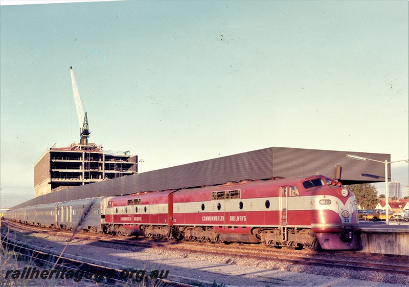 P15869
Commonwealth Railways (CR) GM class 23, GM class 19, double heading passenger train of stainless steel cars, standing at East Perth terminal, Westrail Centre under construction, side and front view
