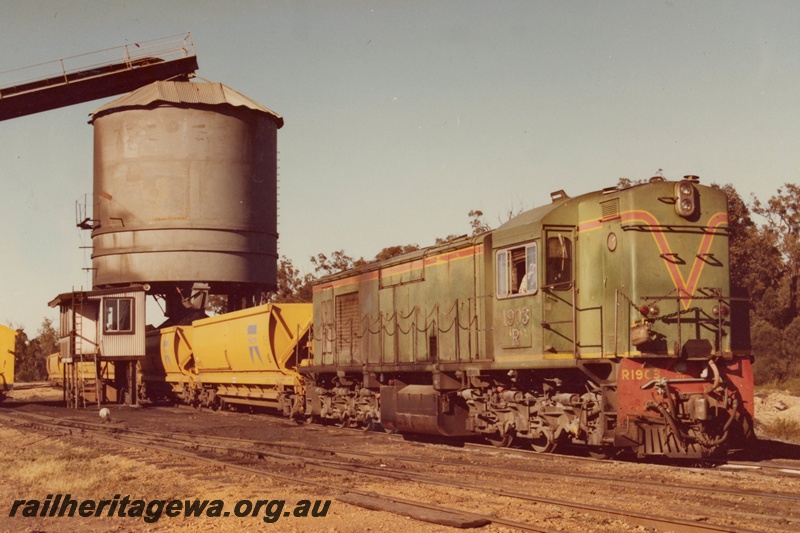 P15968
R class 1903, in green with red and yellow stripe, with side chains, on coal train of XG class hopper wagons being loaded from above, side and front view 
