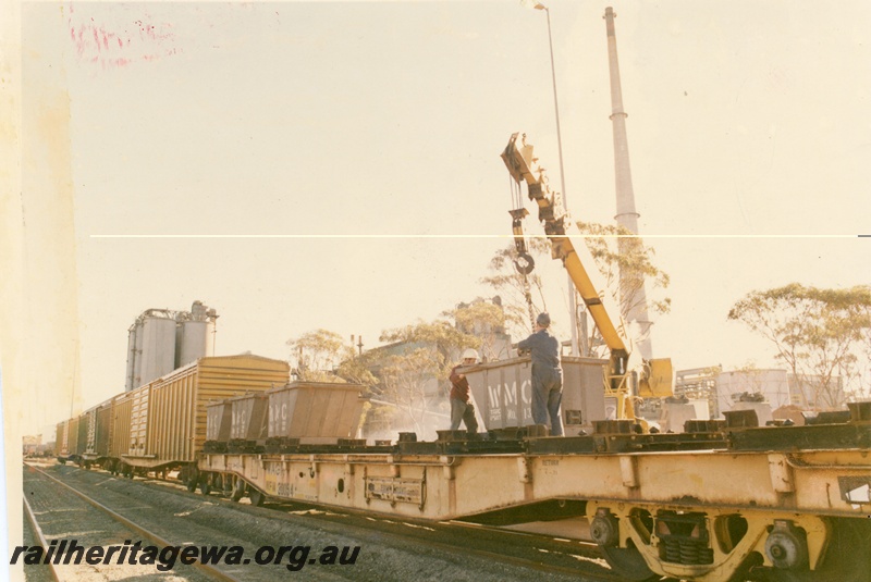 P16023
WFM class 30054, flat wagon, being loaded by crane with WMC containers, workers, WVX vans, later reclassified as WBAX, silos, side and end view from track level 
