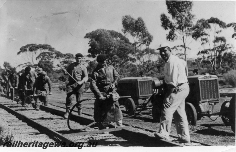 P16098
Railway gang carrying out tracklaying tasks on the Eastern Goldfields section of railway. Early model compressors are noted in the right background.
