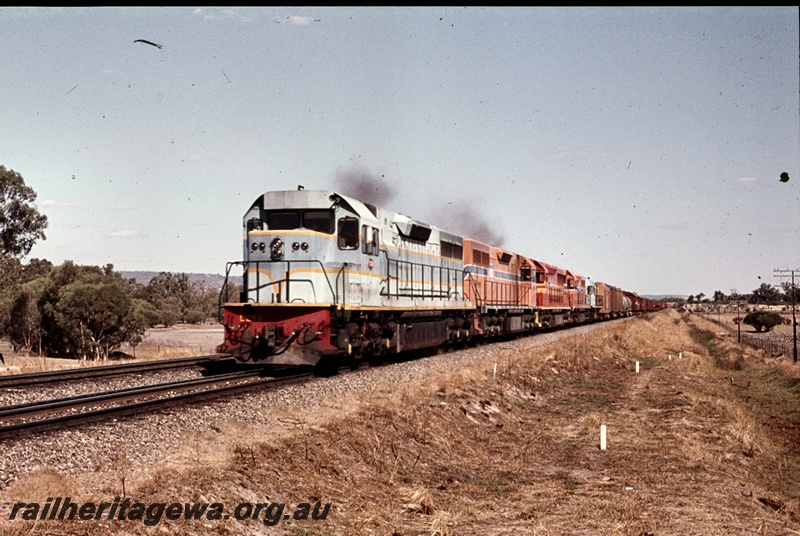 P16669
L class loco, coupled with four other diesel locos, heading a freight train along dual gauge track, rural setting, front and side view
