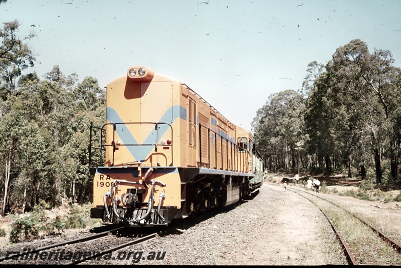 P16680
RA class 1908, in Westrail orange with blue stripe, on excursion train comprising green and cream carriages, passengers on tracks, bush setting, front and side view
