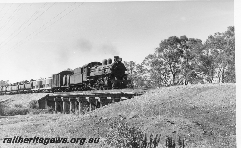 P17032
PR class 523 hauling a goods train over a wooden bridge between York & Narrogin on the GSR line. Note the cement hopper wagons and fuel tanks in the load.
