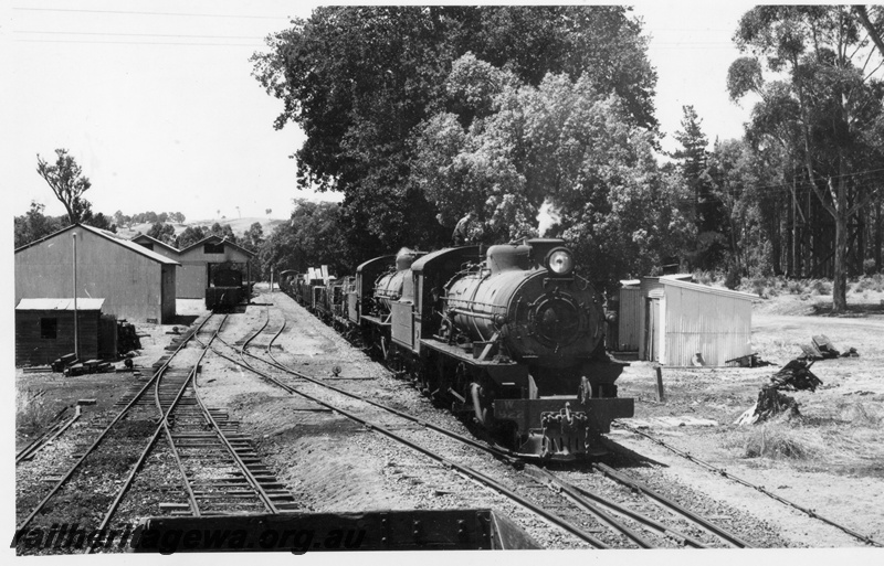 P17453
W class 922 & 940 hauling 344 goods Bridgetown to Bunbury departing Mullalyup on PP line. Gangers shed to right of train, part of wagon in foreground and wagons on goods road.
