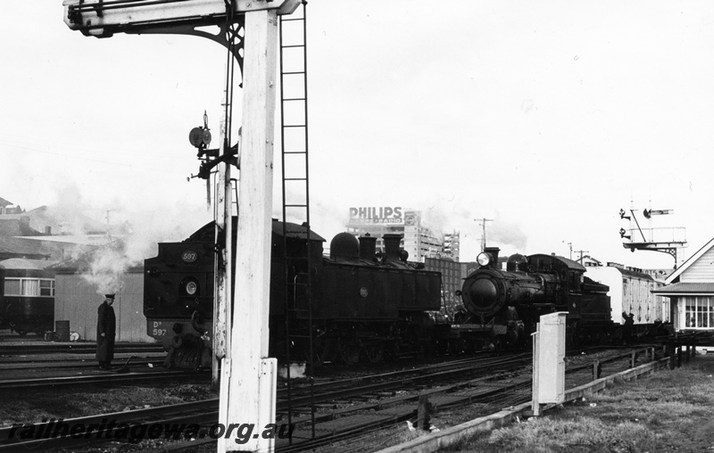 P17728
DD class 597 steam locomotive running light engine, crossing an F class steam locomotive on a goods train, signal box, signals, relay box.
