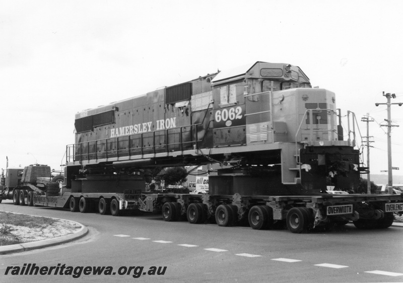 P18118
3 of 4 Hamersley Iron 6062 class diesel locomotive being road hauled from Kewdale to Dampier. Height of load is evident in this view.
