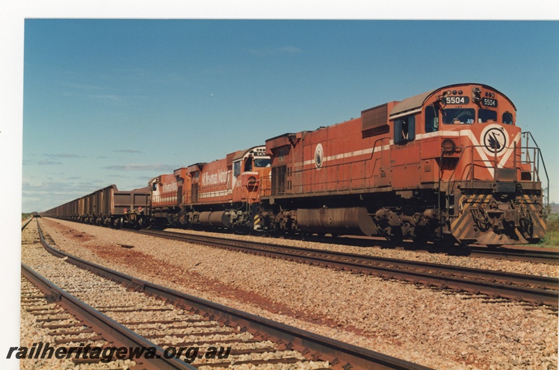 P18764
Mount Newman (MNM) M636 class 5504, 5571 haul a 240 Locotrol ore car at Gidgi.
