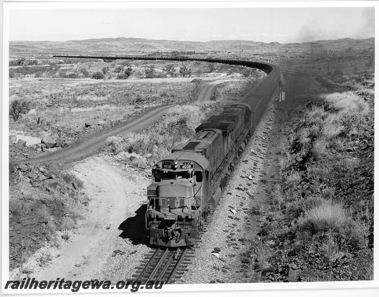 P18833
Hamersley Iron (HI) M636 class 4038, 4033 depart Emu with a loaded iron ore train. Chichester Range in background.
