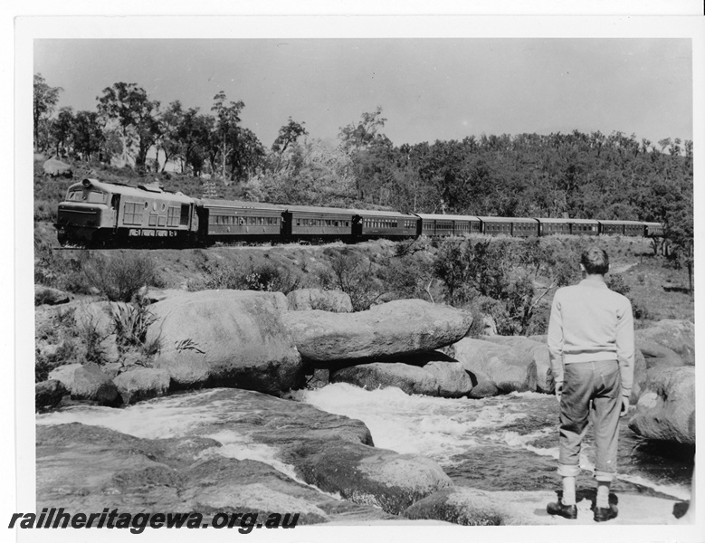 P20019
X class diesel on passenger train, with waterbags hanging from some carriages, rapids and sightseer in foreground, National Park, ER line
