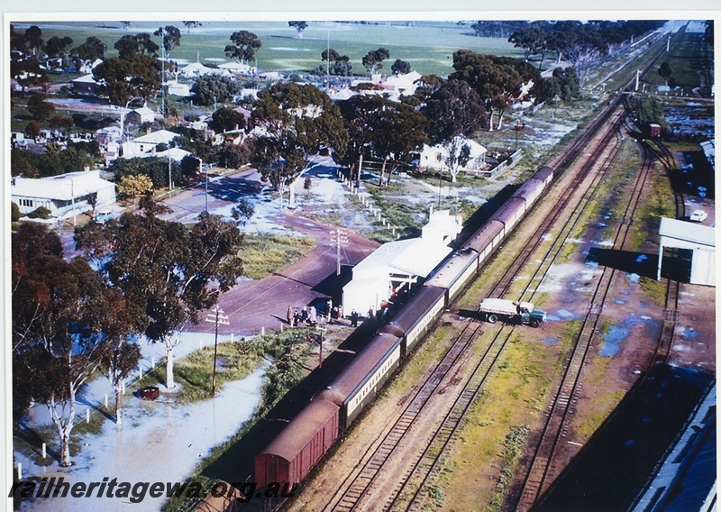 P20032
The Westland Passenger train stopped at Tammin due to floods. Station building, onlookers, town buildings, fields, sidings, points, van, goods shed, signals, truck parked across tracks, Tammin, EGR line, aerial view

