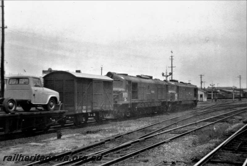 P21628
XB class 1020, XA class1414, double heading goods train including van and flat wagon with motor truck on board, Fremantle bound, signals, points, Perth, ER line, end and side view from track level 
