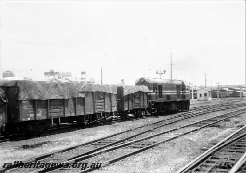 P21634
Ex MRWA G class 50, in MRWA livery, on wheat train to Fremantle, signals, trackside building, points, wagons, Perth, ER line, end and side view from track level 
