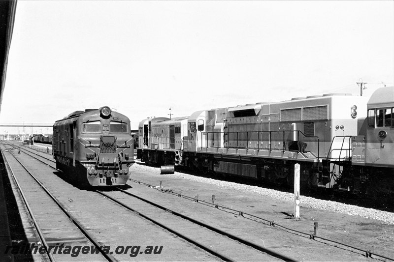 P22818
XA class 1404 on loop from loco depot, standard gauge H class loco and two L class locos in yard, pedestrian overpass, signals, Kalgoorlie, EGR line, side and end view 

