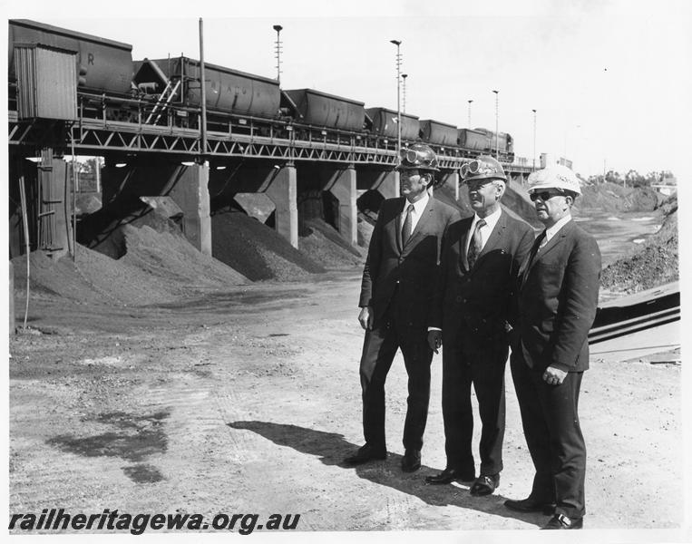 P00197
XC class bauxite wagons on the unloader at Alcoa, Kwinana, group of officials in the foreground

