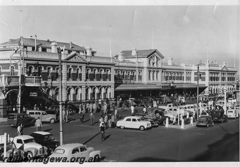 P00319
Perth station, view along the street side looking east with cars parked in the forecourt, extra description on rear of the photo. C1963
