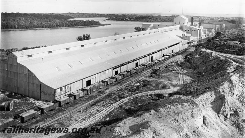 P00379
Fertilizer works, Rocky Bay Line, line of loaded wagons including an unrebuilt RA class bogie open wagon, elevated view of site looking west.
