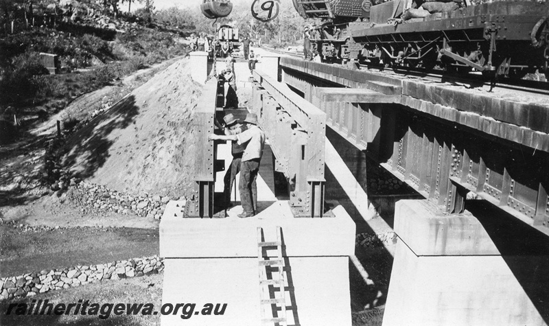 P01436
11 of 13 images of the construction of the duplicate steel girder bridge No.1 at 16 miles 25 chains on the ER through the John Forrest National Park, main girder being placed into position on pylons.
