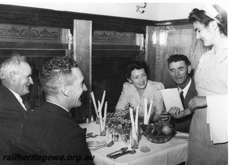 P01442
Internal view of an AV class dining car, waitress showing seated passengers the menu
