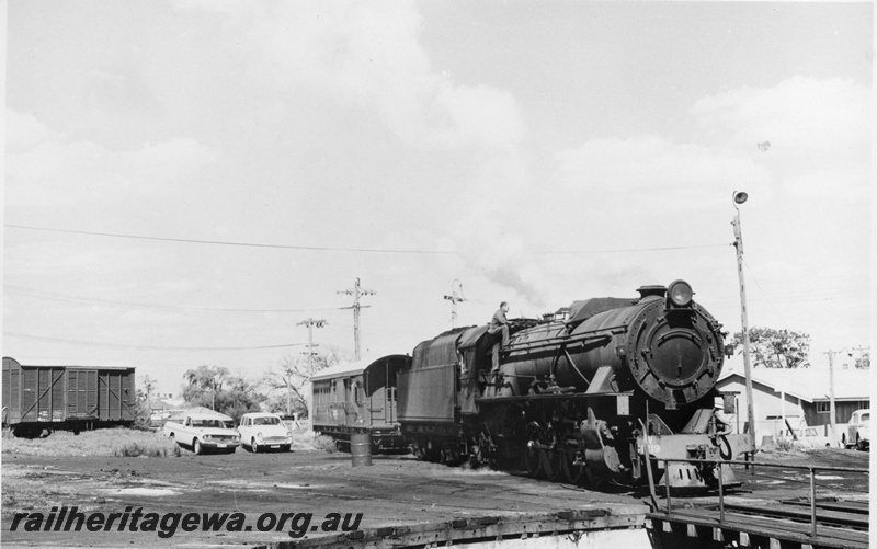 P02410
1 of 2. V class 1219 steam locomotive, side and front view, approaching turntable, louvered van and brakevan in the background, Bunbury, SWR.
