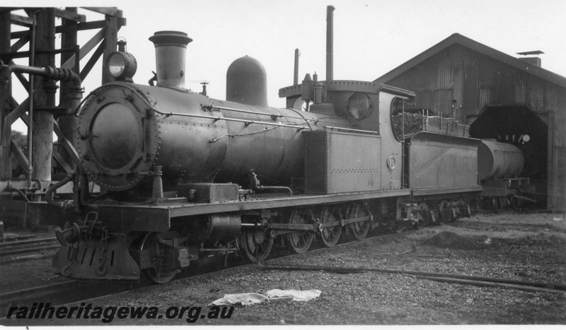 P02724
O class 98 steam locomotive, front and side view, outside loco shed, next to water tower, Busselton, BB line.
